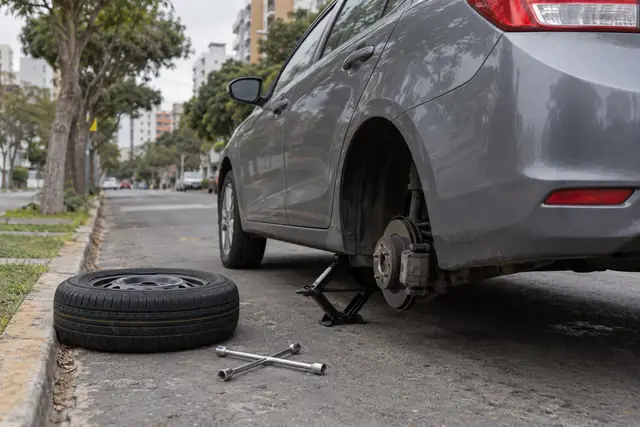 Auto levantado con gata y la llanta de repuesto al lado